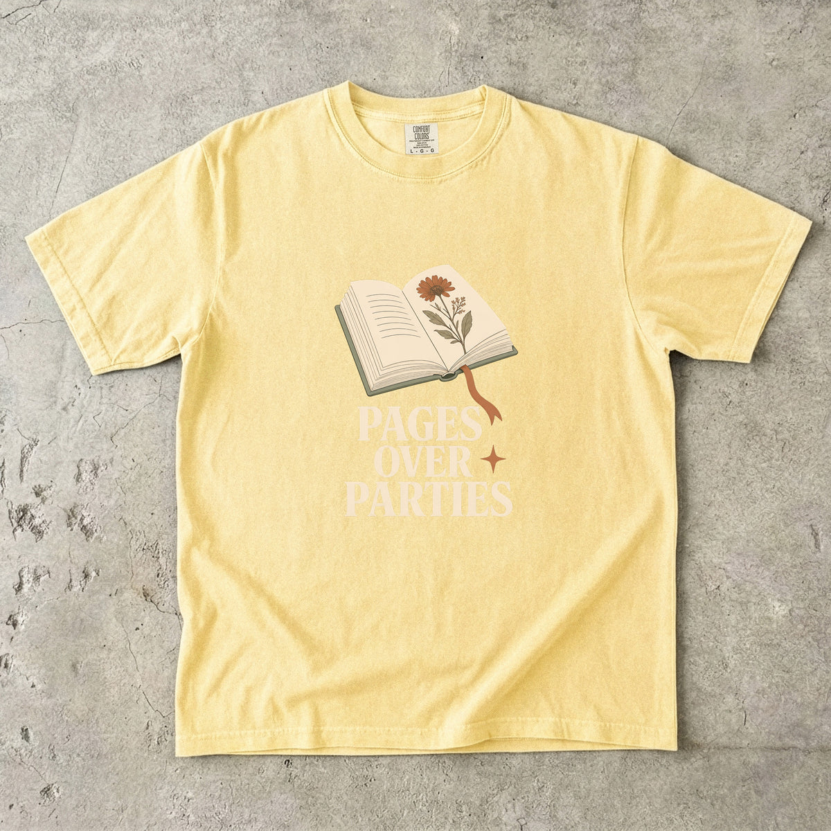 Pages Over Parties introvert reader shirt in Butter featuring an open book, flower and bold book lover statement.