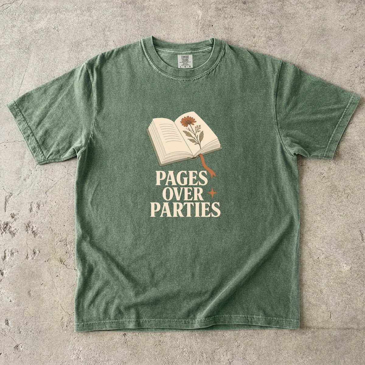 Pages Over Parties introvert reader shirt in Moss featuring an open book, pressed flower and bold cream typography.