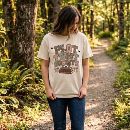 Reader wearing an Ivory Plot Twist Society Comfort Colors T-shirt outdoors, featuring a playful retro book lover design.