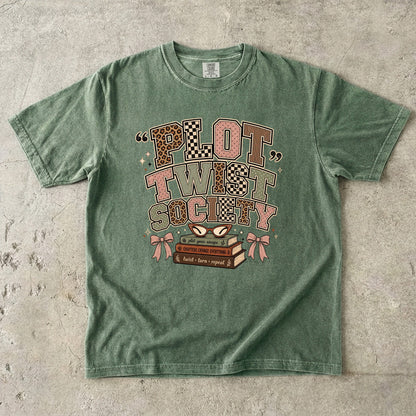 Moss Comfort Colors book lover T-shirt featuring the retro Plot Twist Society graphic with stacked books and glasses.