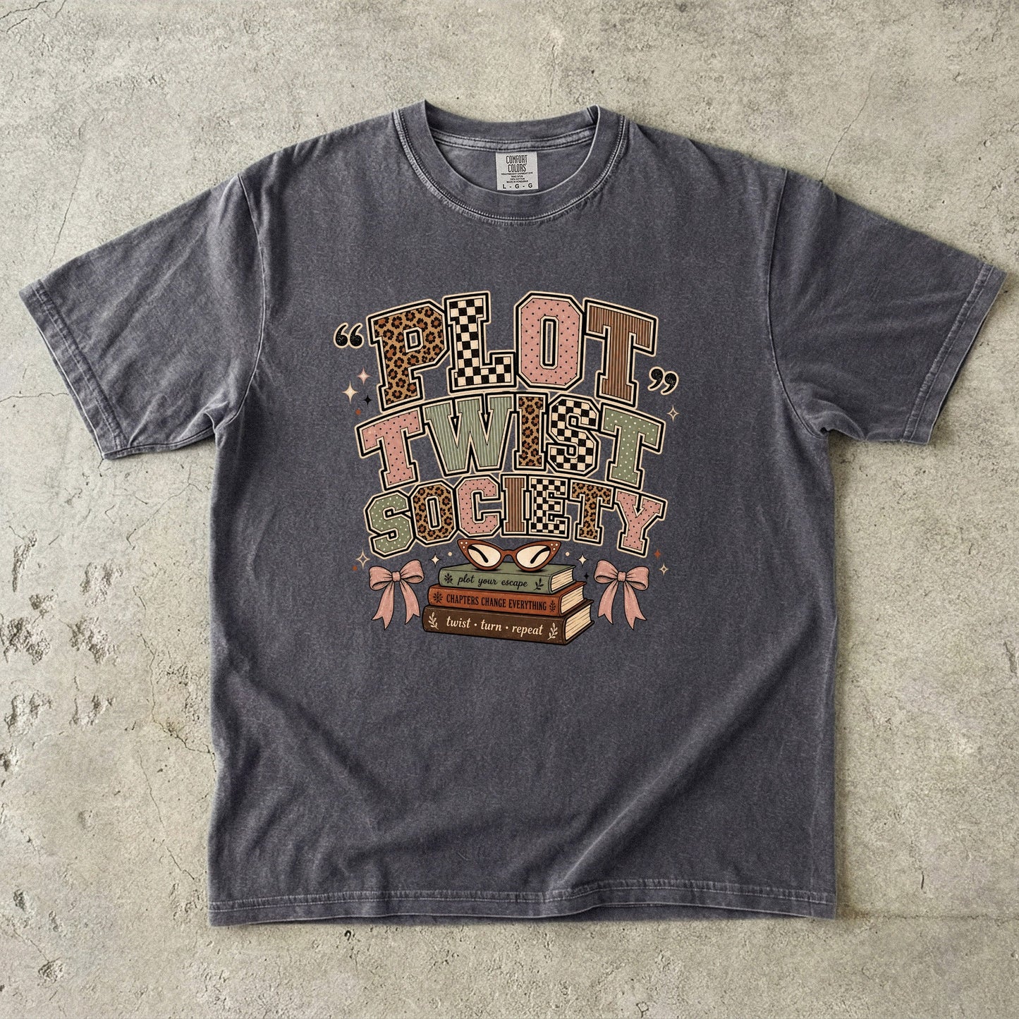 Pepper Comfort Colors book lover T-shirt featuring the playful retro Plot Twist Society design with books and reading glasses.