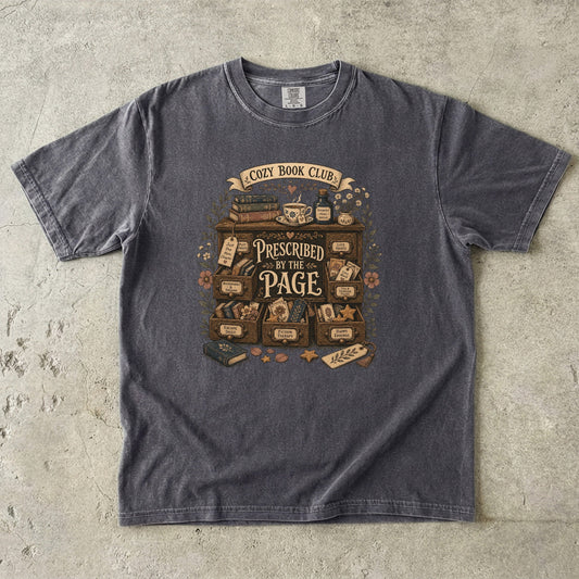 Prescribed by the Page cozy book club T-shirt in Pepper featuring a vintage literary cabinet filled with books, tea and reading-themed drawers