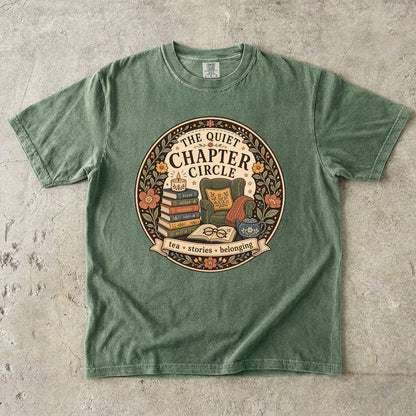 Quiet Chapter Circle book club T-shirt with armchair, stacked books, teapot and floral reading design on Moss.