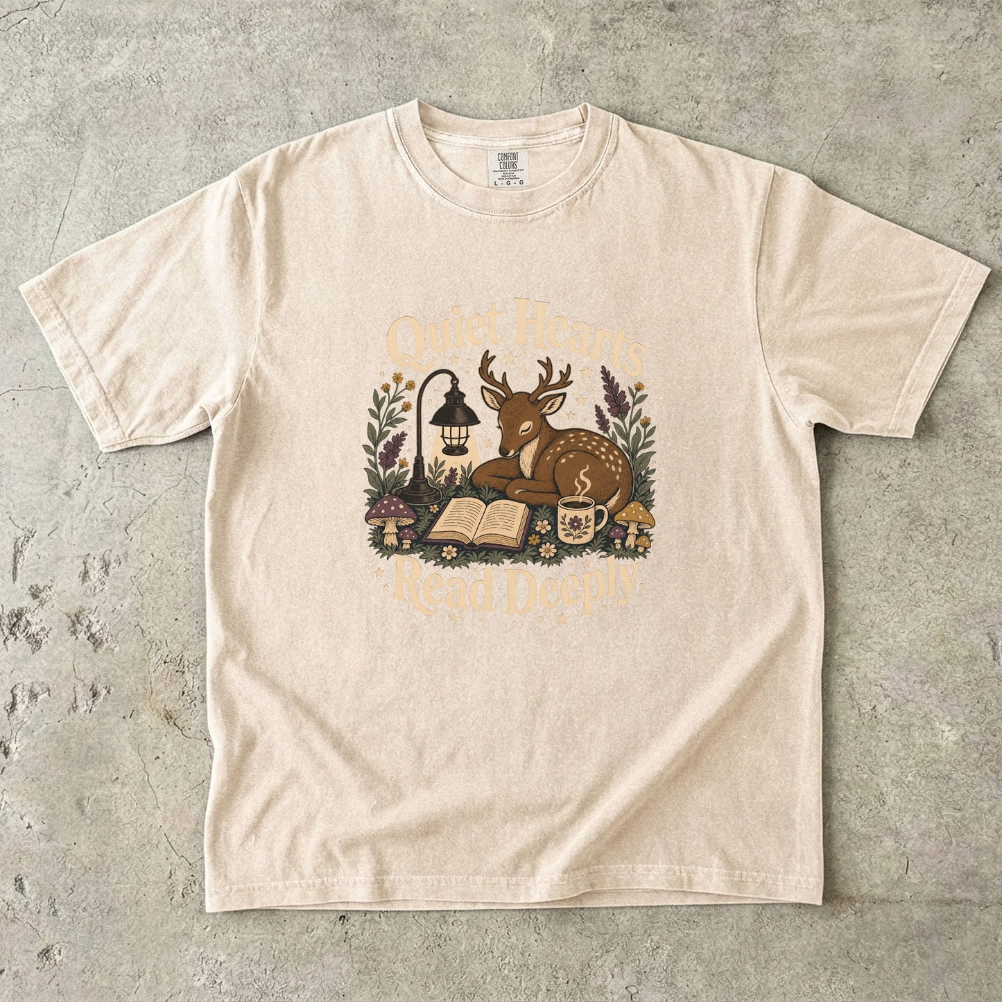 Front view of the Ivory Comfort Colors® Book Lover T-shirt featuring the Quiet Hearts Read Deeply literary woodland illustration.