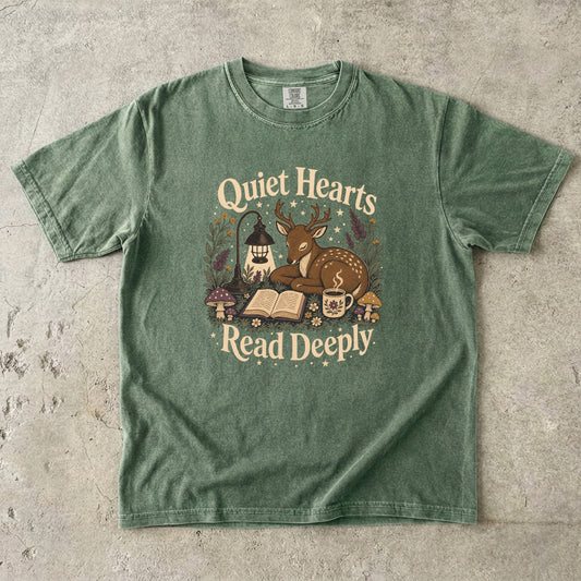 Front view of the Moss Comfort Colors® Book Lover T-shirt featuring the Quiet Hearts Read Deeply design with a woodland deer, open book, lantern and tea.