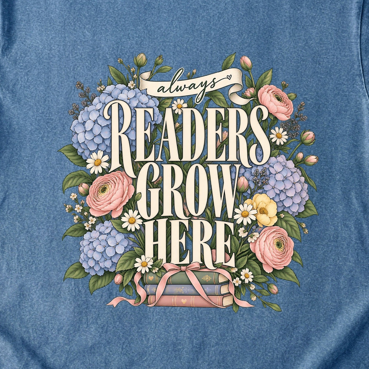 Close-up of the “always READERS GROW HERE” T-shirt design, showing large cream lettering surrounded by pastel blue flowers, pink blooms, daisies, leaves and ribbon-tied books.