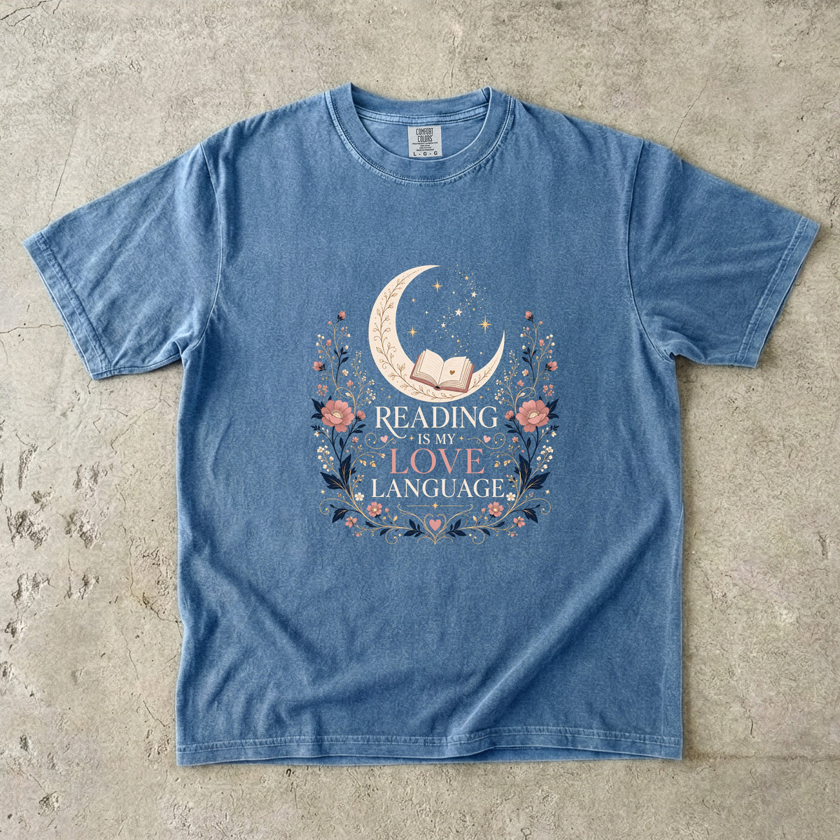 Blue Jean book lover T-shirt featuring Reading Is My Love Language with an open book, crescent moon, stars and pink floral details.
