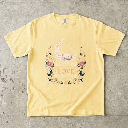 Butter book lover T-shirt featuring Reading Is My Love Language with an open book, crescent moon, stars and pink floral details.
