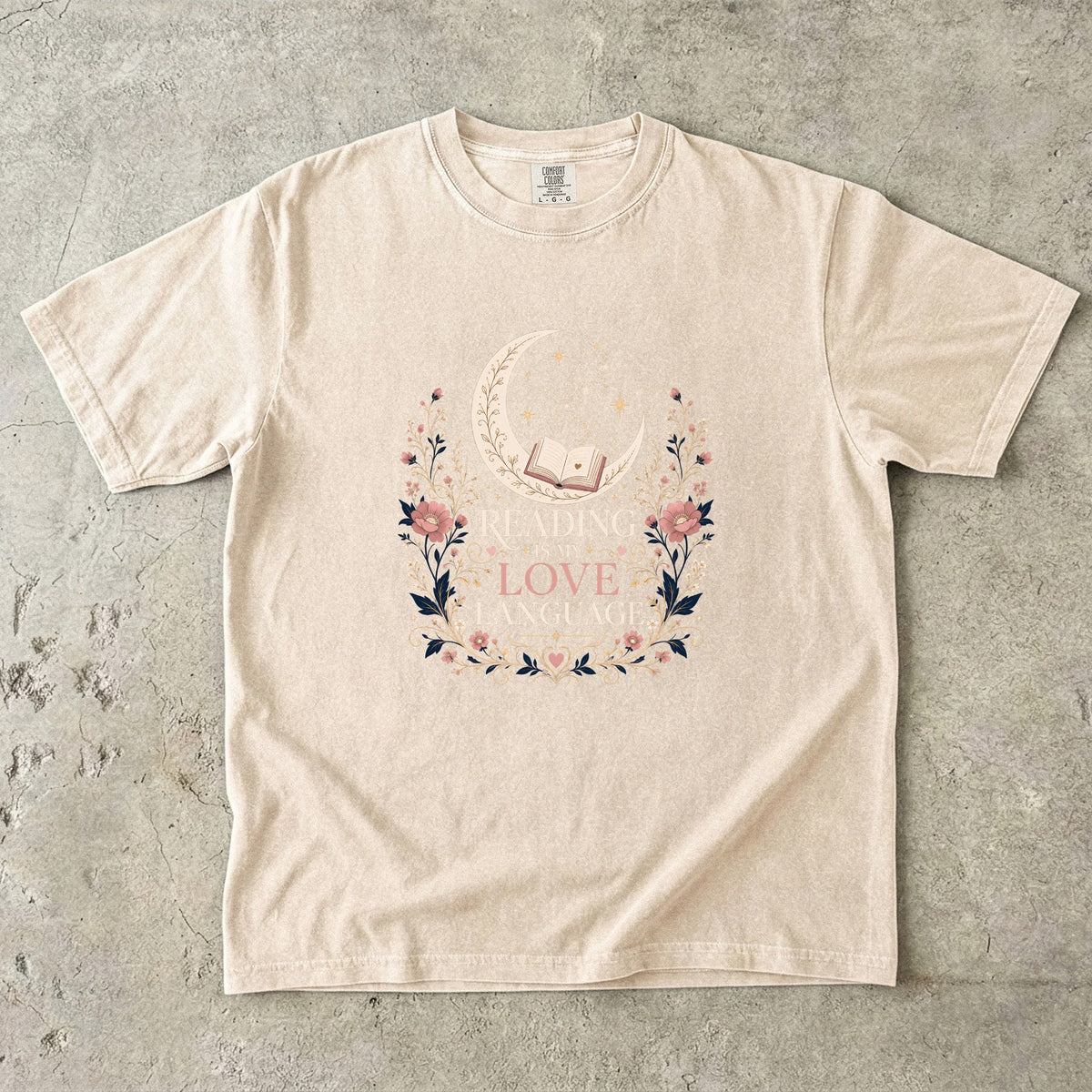 Ivory book lover T-shirt featuring Reading Is My Love Language with an open book, crescent moon, stars and pink floral details.