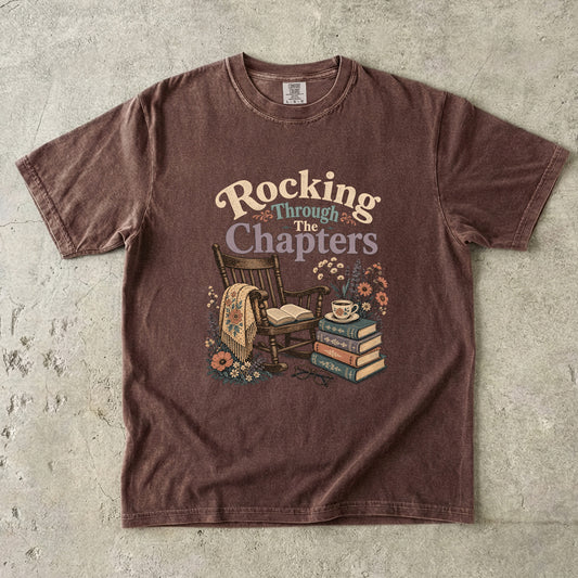 Front view of an Espresso Comfort Colors® book lover T-shirt featuring the Rocking Through the Chapters design with a vintage rocking chair, stacked books, teacup and cottage flowers.