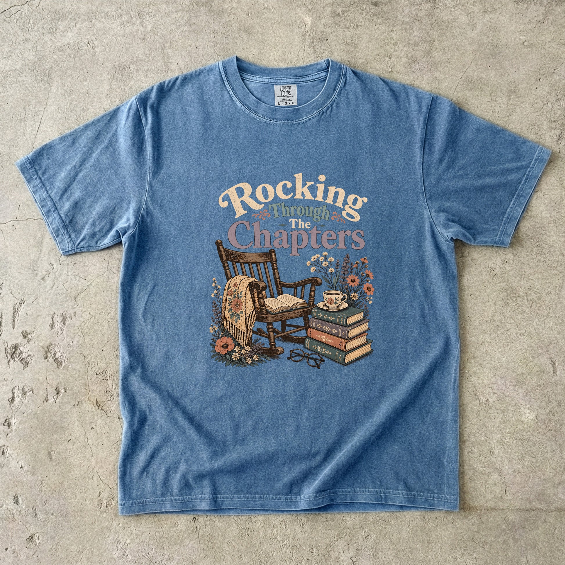 Rocking Through the Chapters cozy reading T-shirt in Blue Jean featuring a vintage rocking chair, open book, stacked books and teacup