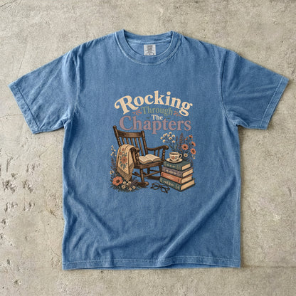 Rocking Through the Chapters cozy reading T-shirt in Blue Jean featuring a vintage rocking chair, open book, stacked books and teacup