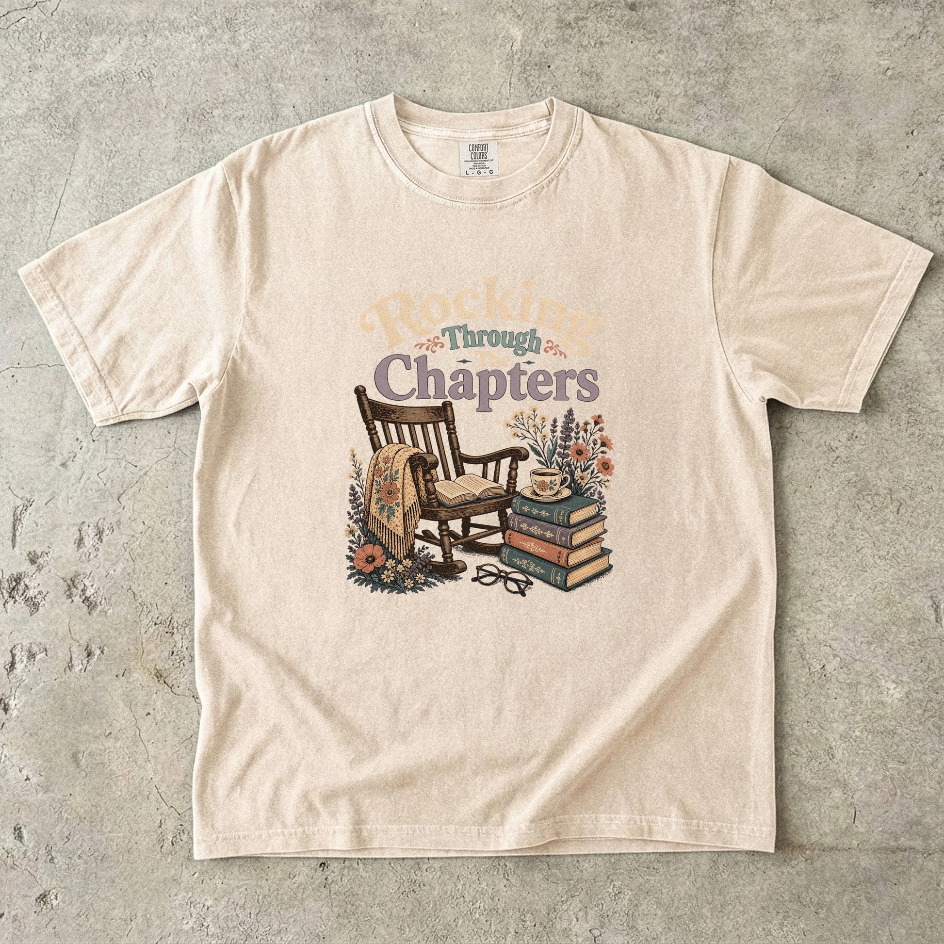 Rocking Through the Chapters cozy reading T-shirt in Ivory featuring a vintage rocking chair, open book, stacked books and teacup