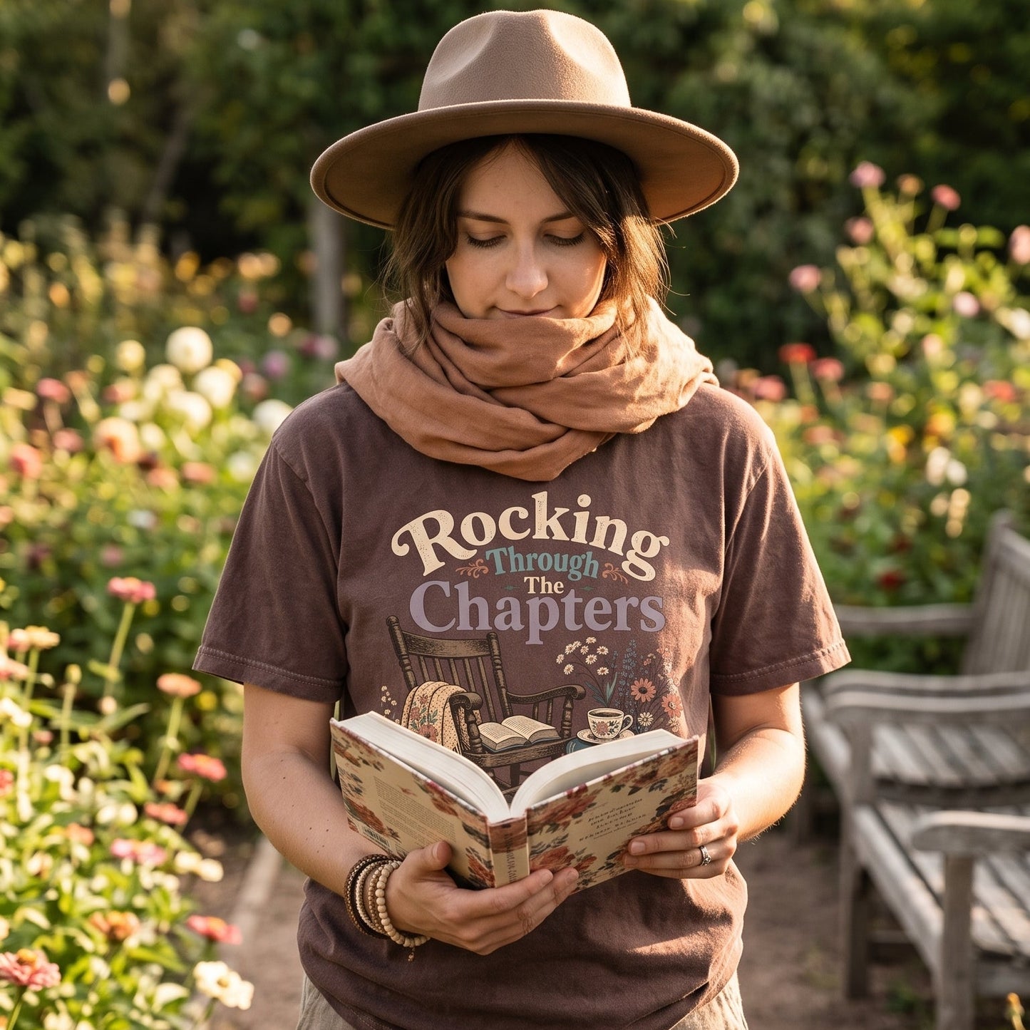 Rocking Through the Chapters cozy reading T-shirt featuring a rocking chair, open book, floral blanket, stacked books, teacup and flowers