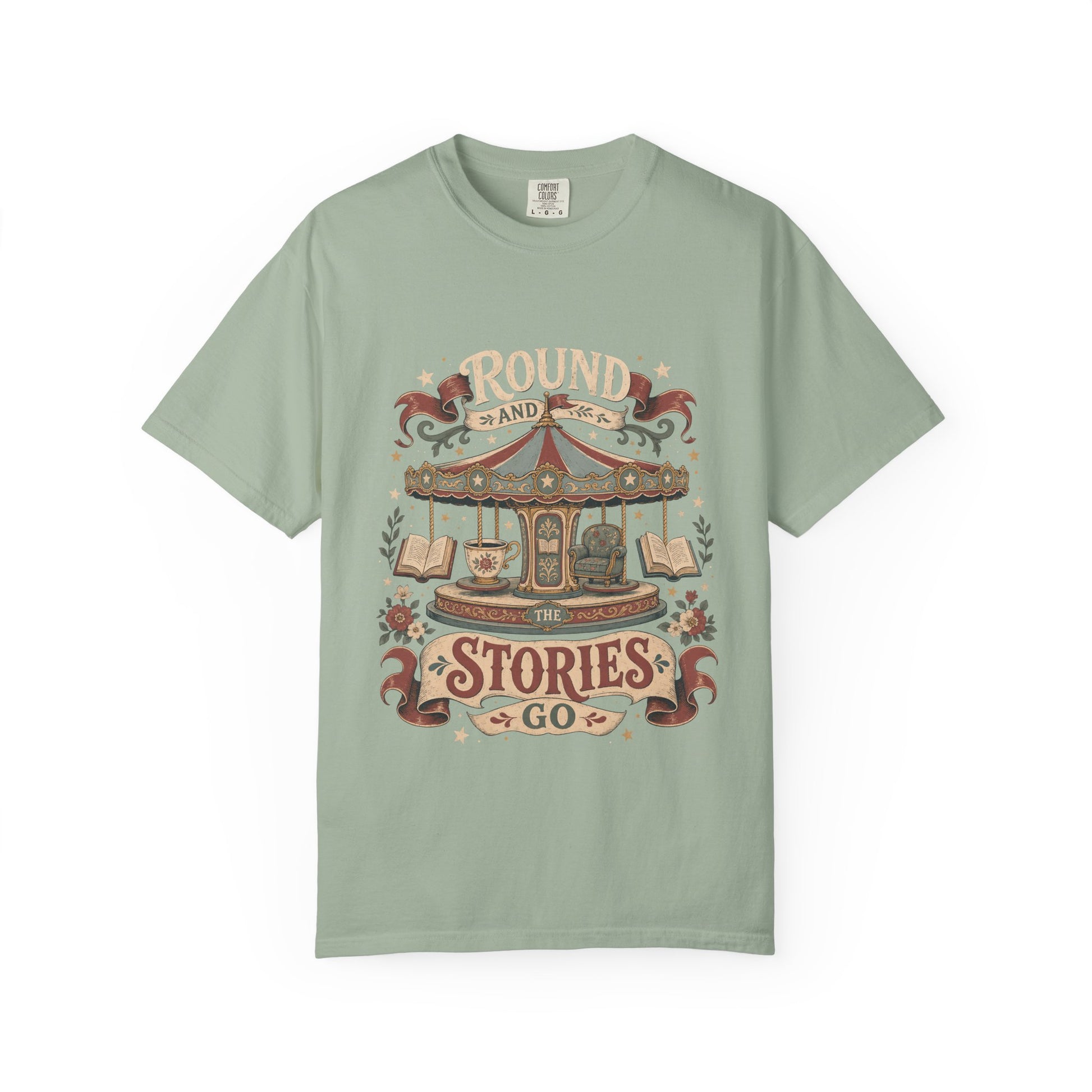 Front view of a Bay Comfort Colors® book lover T-shirt featuring the "Round and Round the Stories Go" vintage carousel, books, teacup and reading chair illustration.