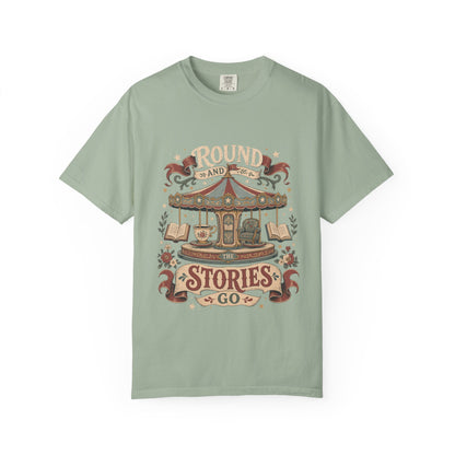 Front view of a Bay Comfort Colors® book lover T-shirt featuring the "Round and Round the Stories Go" vintage carousel, books, teacup and reading chair illustration.