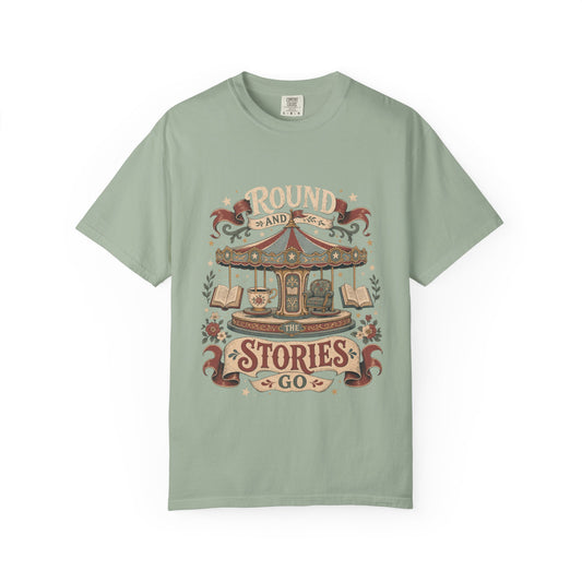 Front view of a Bay Comfort Colors® book lover T-shirt featuring the "Round and Round the Stories Go" vintage carousel, books, teacup and reading chair illustration.