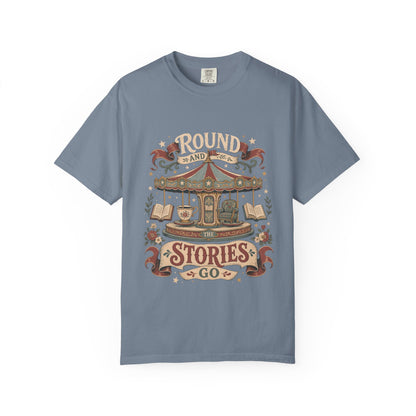 Round and Round the Stories Go book lover T-shirt in Blue Jean featuring a vintage carousel with open books, reading chair and teacup