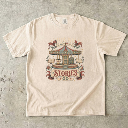 Round and Round the Stories Go book lover T-shirt in Ivory featuring a vintage carousel with open books, reading chair and teacup