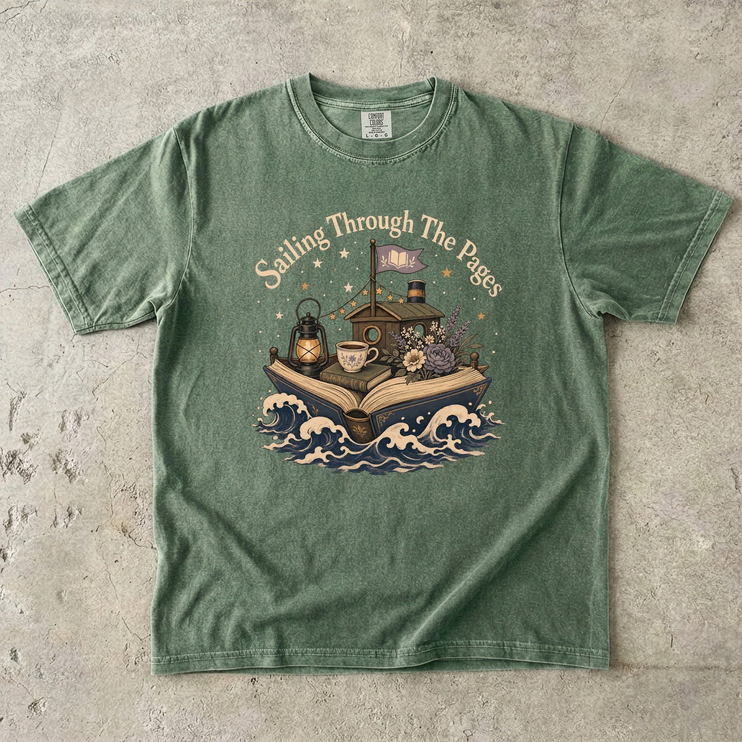 Front view of a Moss Comfort Colors Book Lover T-shirt featuring the Sailing Through the Pages illustration with an open book boat, lantern, teacup and flowers.