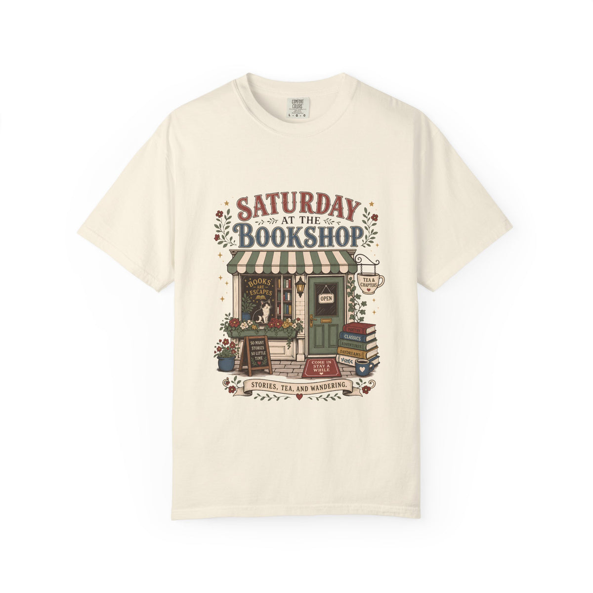 Saturday at the Bookshop book lover T-shirt featuring a cozy bookstore, stacked books, flowers, cat and tea details on Ivory.