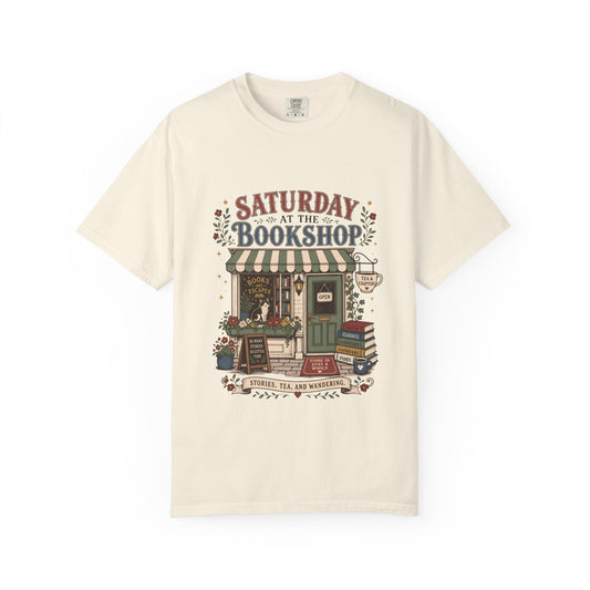 Saturday at the Bookshop book lover T-shirt featuring a cozy bookstore, stacked books, flowers, cat and tea details on Ivory.