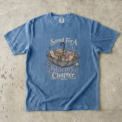 Saved for a Stormy Chapter reading T-shirt in Blue Jean featuring an umbrella filled with books, tea, bookmarks and flowers