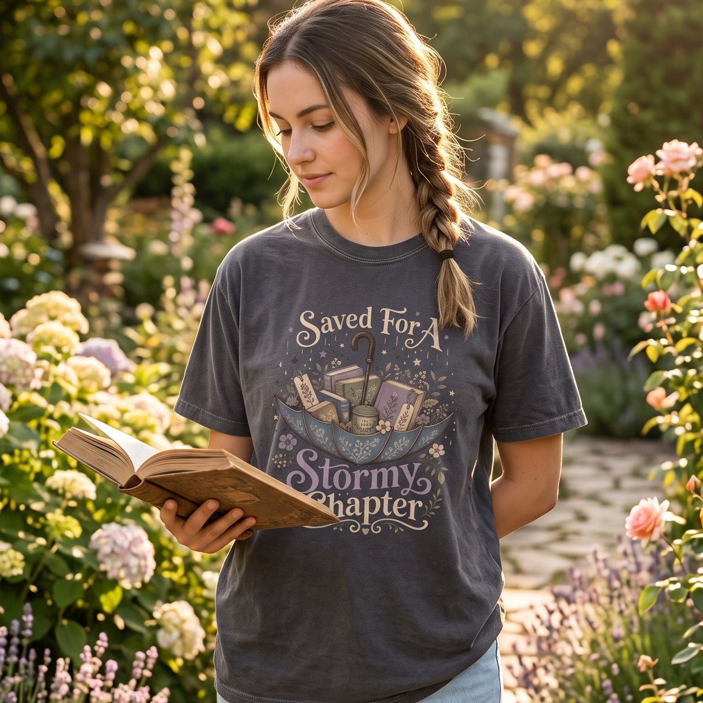 Saved for a Stormy Chapter rainy day reading T-shirt featuring a floral umbrella overflowing with books, tea and bookmarks