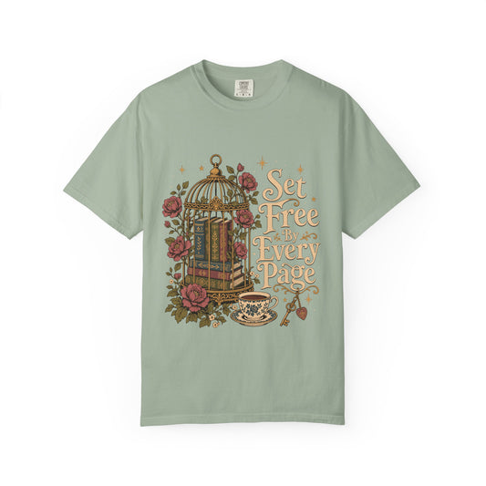 Front view of a Bay Comfort Colors T-shirt featuring the "Set Free By Every Page" vintage literary design with books inside an ornate birdcage, roses, teacup and decorative key.