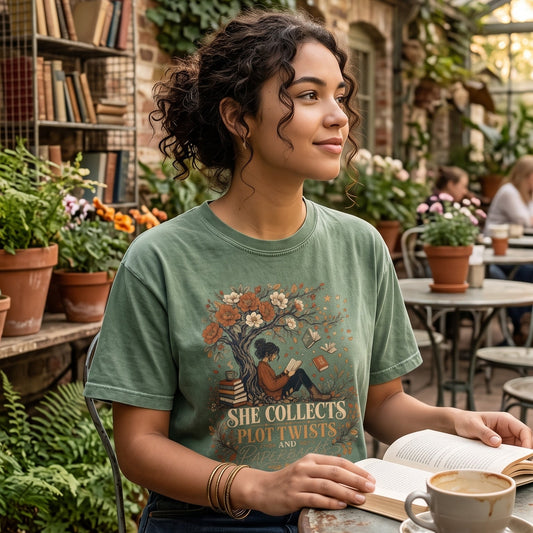 She Collects Plot Twists and Paperbacks reading T-shirt featuring a reader beneath a flowering tree surrounded by books and leaves.
