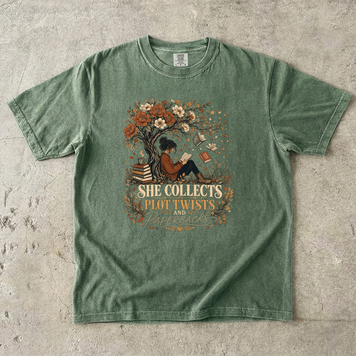 Moss reading T-shirt featuring She Collects Plot Twists and Paperbacks with a reader beneath a flowering tree surrounded by books.
