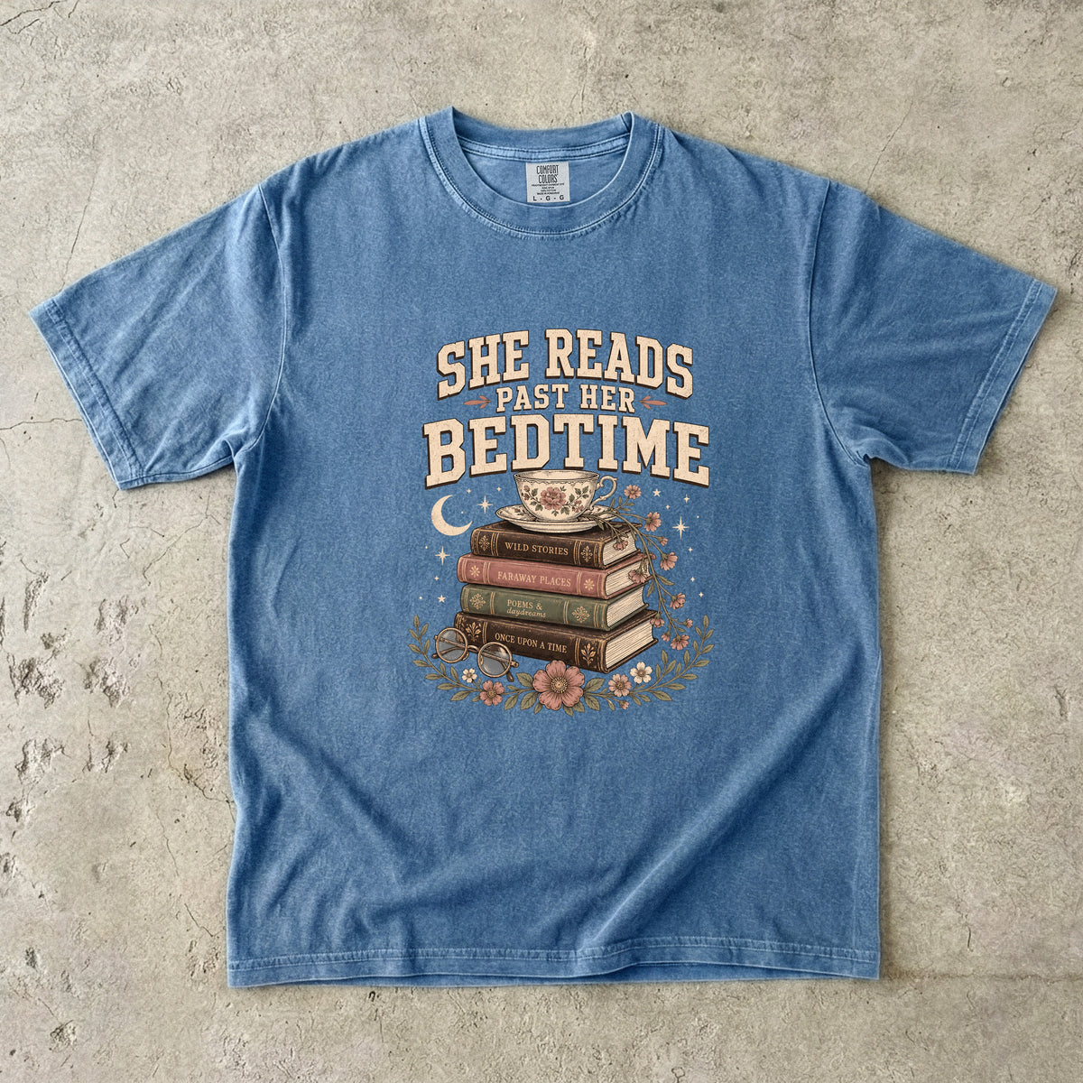 Blue Jean reading T-shirt featuring She Reads Past Her Bedtime with stacked books, a floral teacup, flowers and crescent moon.