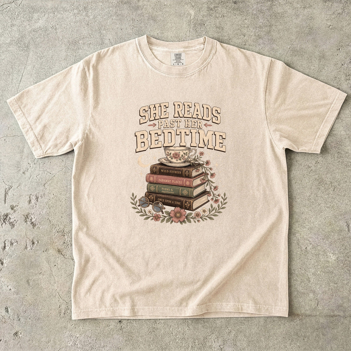Ivory reading T-shirt featuring She Reads Past Her Bedtime with stacked books, a floral teacup, flowers and crescent moon.