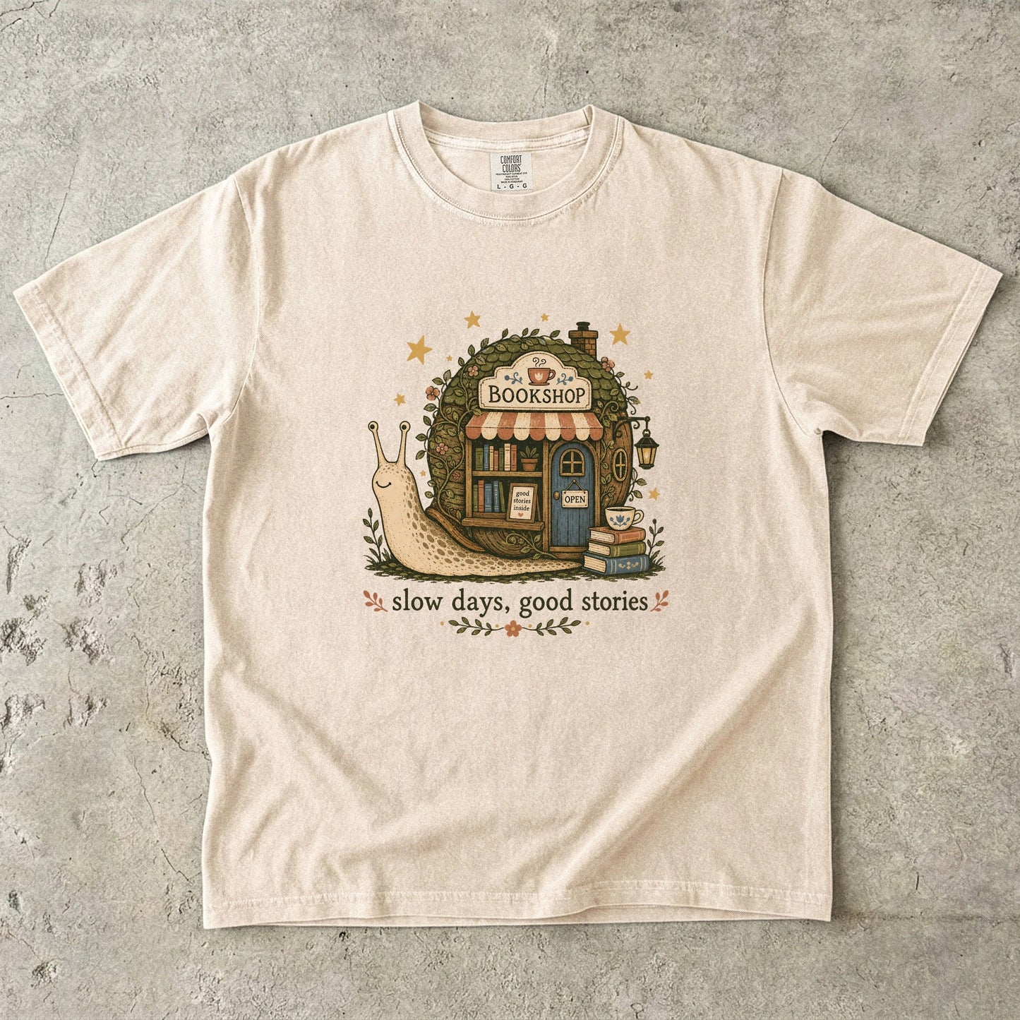 Slow Days, Good Stories Book Lover Shirt printed on an Ivory Comfort Colors 1717 T-shirt featuring a whimsical woodland bookshop design.

