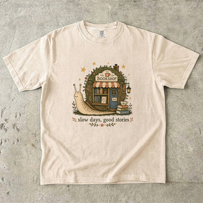Slow Days, Good Stories Book Lover Shirt printed on an Ivory Comfort Colors 1717 T-shirt featuring a whimsical woodland bookshop design.

