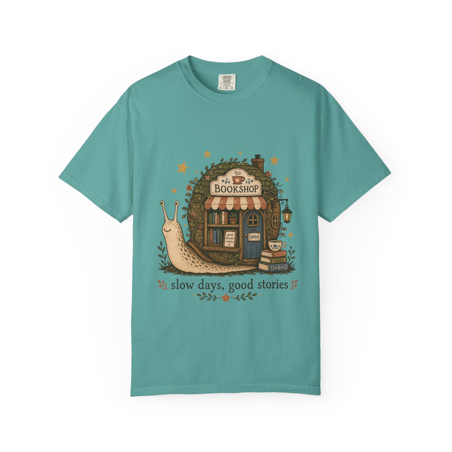 Slow Days, Good Stories Book Lover Shirt on a Seafoam Comfort Colors 1717 T-shirt with a whimsical snail bookshop illustration.

