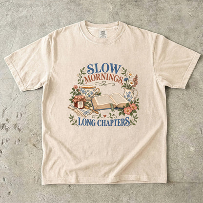 Ivory T-shirt featuring “Slow Mornings, Long Chapters” with an open book, blue floral teacup and pitcher, a jam jar, spoon, flowers and checked cloth.
