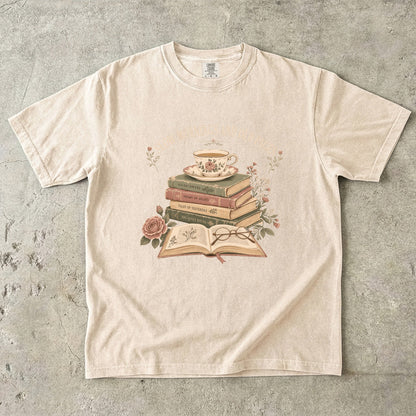 Ivory reading T-shirt featuring Slow Mornings and Old Pages with stacked vintage books, a floral teacup, open book, glasses and roses.
