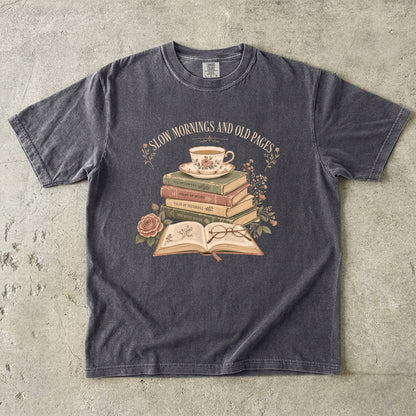 Pepper reading T-shirt featuring Slow Mornings and Old Pages with stacked vintage books, a floral teacup, open book, glasses and roses.