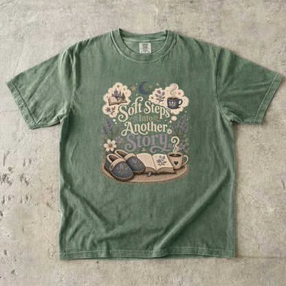 Soft Steps Into Another Story cozy reading T-shirt in Moss featuring slippers, an open book, flowers and a warm drink
