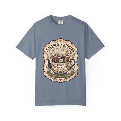 Steeped in Stories book lover T-shirt with a floral teapot overflowing with books on Blue Jean.