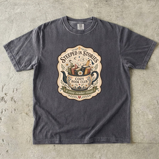 Steeped in Stories book lover T-shirt with a floral teapot overflowing with books on Pepper.