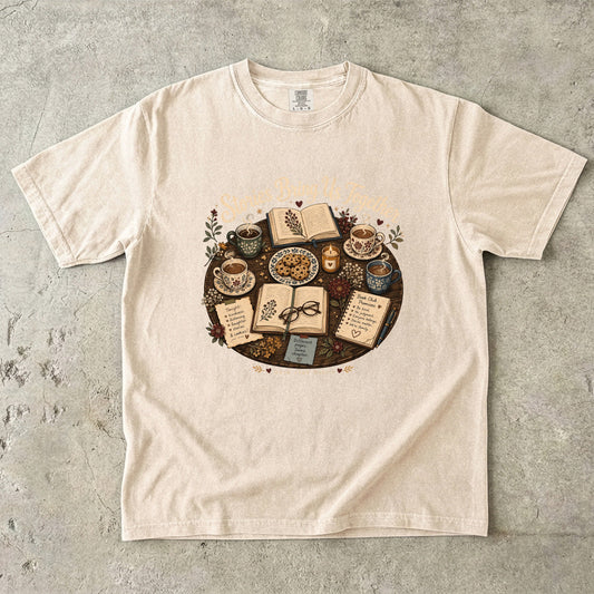 Stories Bring Us Together book club T-shirt featuring open books, tea, cookies and flowers on Ivory.
