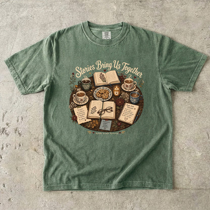 Stories Bring Us Together book club T-shirt featuring open books, tea, cookies and flowers on Moss.