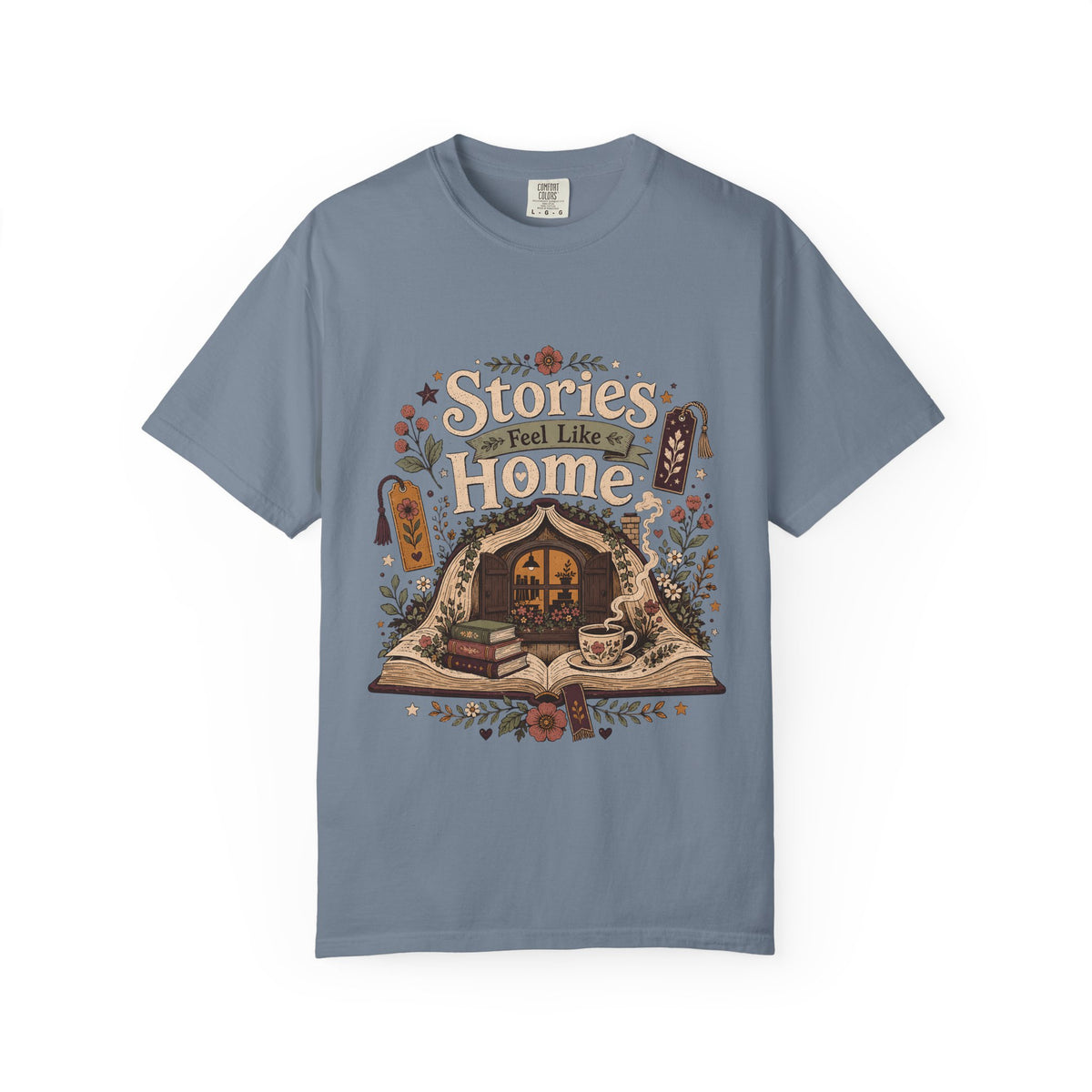 Stories Feel Like Home book lover T-shirt with open book, cozy reading nook, stacked books, teacup and floral details on Blue Jean.