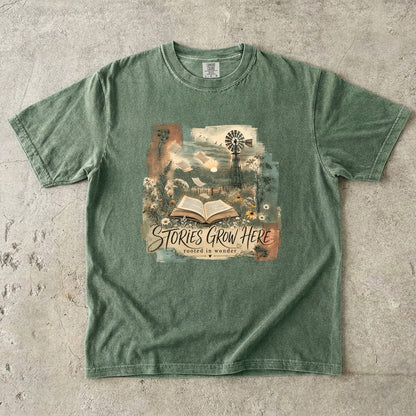 Moss Comfort Colors Stories Grow Here book lover T-shirt featuring a vintage open book and nature illustration.