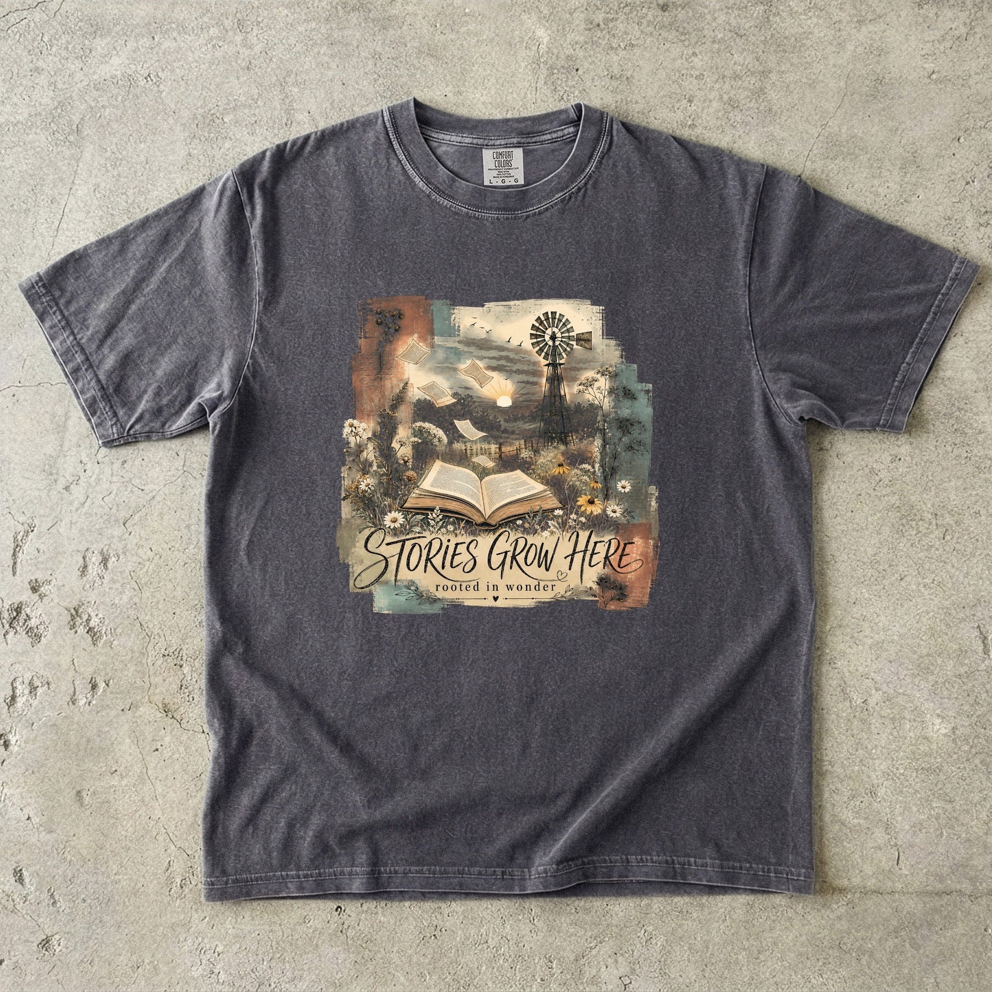 Pepper Comfort Colors Stories Grow Here reading T-shirt with an open book, wildflowers and countryside artwork.