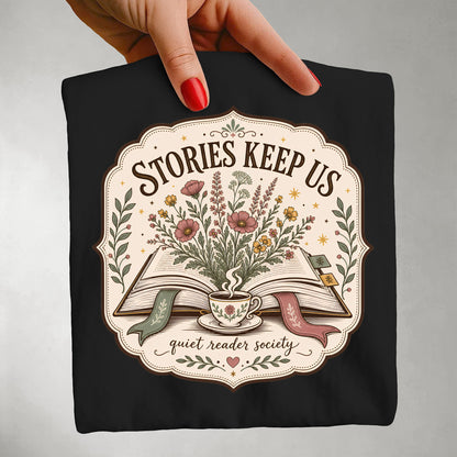 Folded black Stories Keep Us literary graphic T-shirt featuring vintage book-inspired artwork.