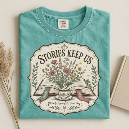 Folded seafoam Stories Keep Us book-inspired T-shirt with floral literary artwork.