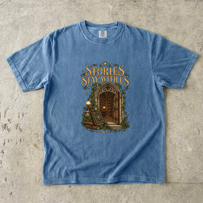 Blue Jean T-shirt featuring “Stories Stay With Us” with an ivy-covered arched library doorway, antique books, lamps and gold stars.